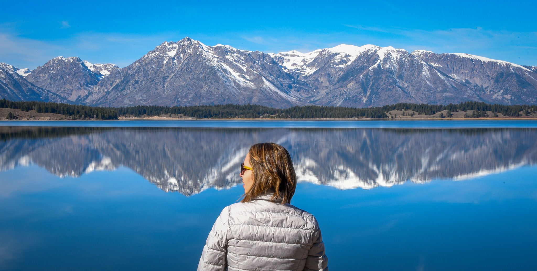 Viajante contemplando um lago com montanhas refletidas na água